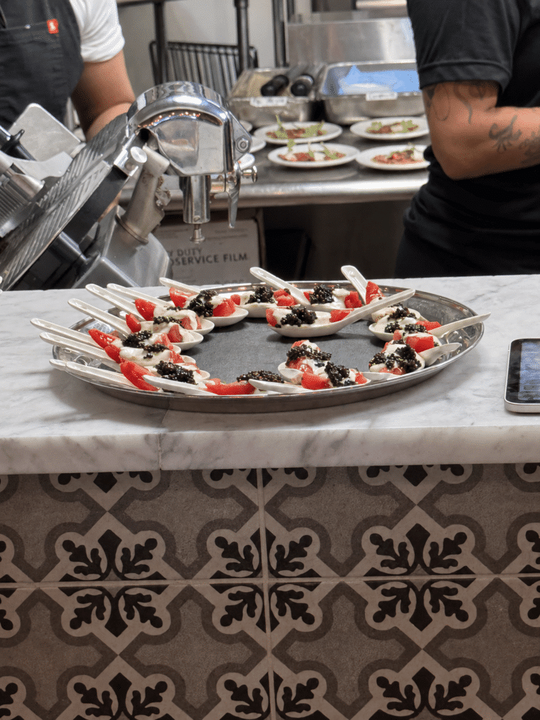 Viaggio x La Valle Dinner Review White tasting spoons filled with the NJ Tomato Bite amuse-bouche, arranged on a silver tray in Viaggio’s kitchen.