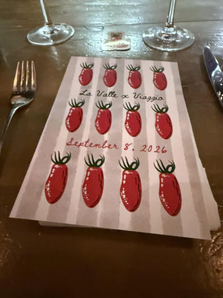 Viaggio x La Valle Menu cover decorated with red tomato illustrations, reading “La Valle x Viaggio” and “September 8, 2026,” between a fork and knife.