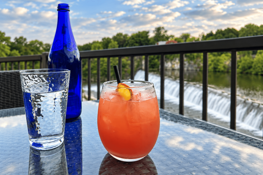 BLACKBARN Hudson Valley Review Pink cocktail on the BLACKBARN patio with Esopus Falls in the background