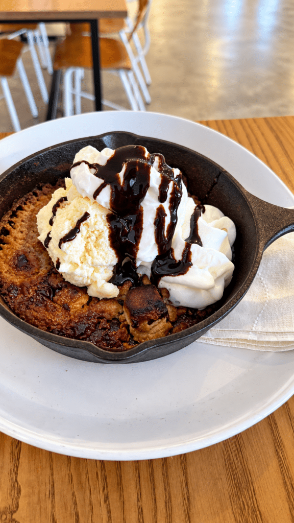 Chocolate chip cookie skillet topped with vanilla bean cheesecake filling and dark chocolate sauce at Drowned Lands.