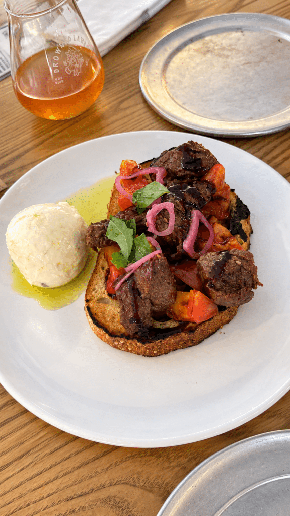 Bavette steak toast topped with beef, heirloom tomatoes, pickled shallots and basil at Drowned Lands Brewery.