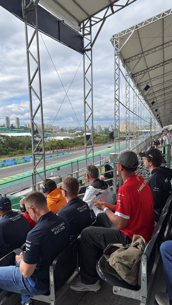 Why I Love Formula 1 Fans wearing clothing from different Formula 1 teams gather in a covered grandstand at Interlagos.