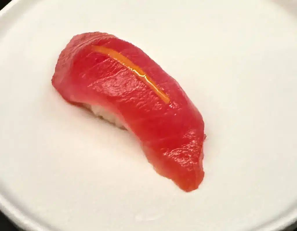 Sushi by Sea Review Red akami nigiri topped with a narrow strip of orange peel.
