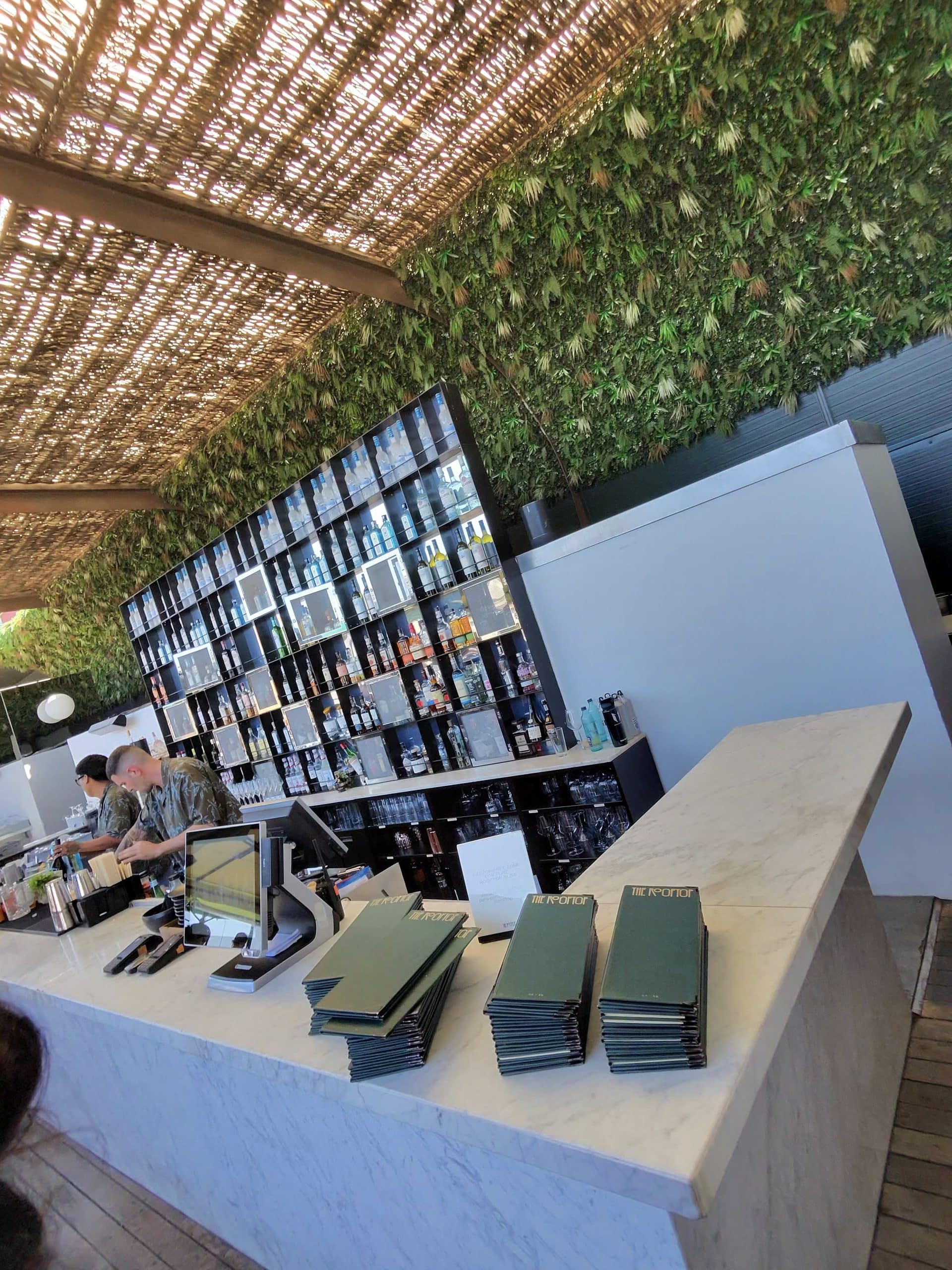 The rooftop bar at Sir Victor in Barcelona, with a leafy wall and bottle display.