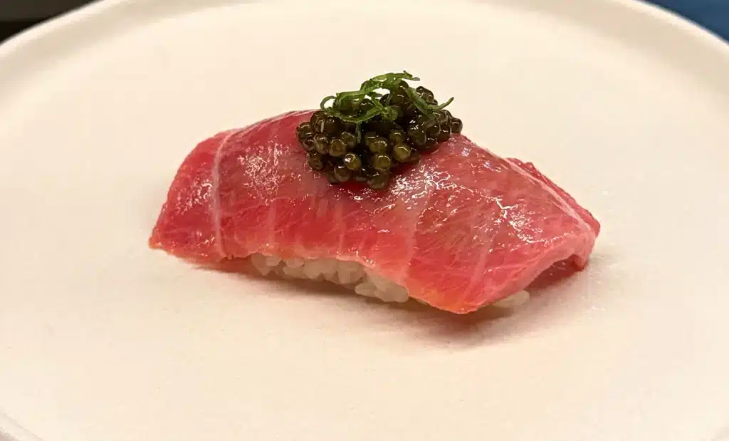 Sushi by Sea Review  Pink, marbled chutoro nigiri topped with caviar and a small green garnish.