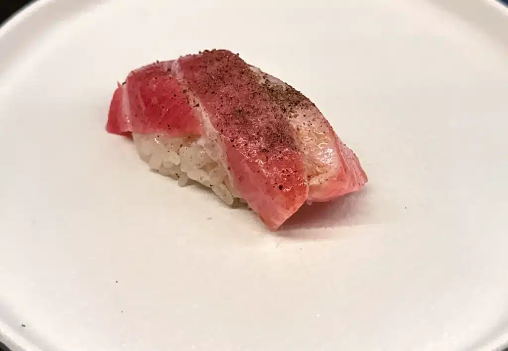 Sushi by Sea Review Pink, marbled otoro nigiri with a darkened surface over rice.