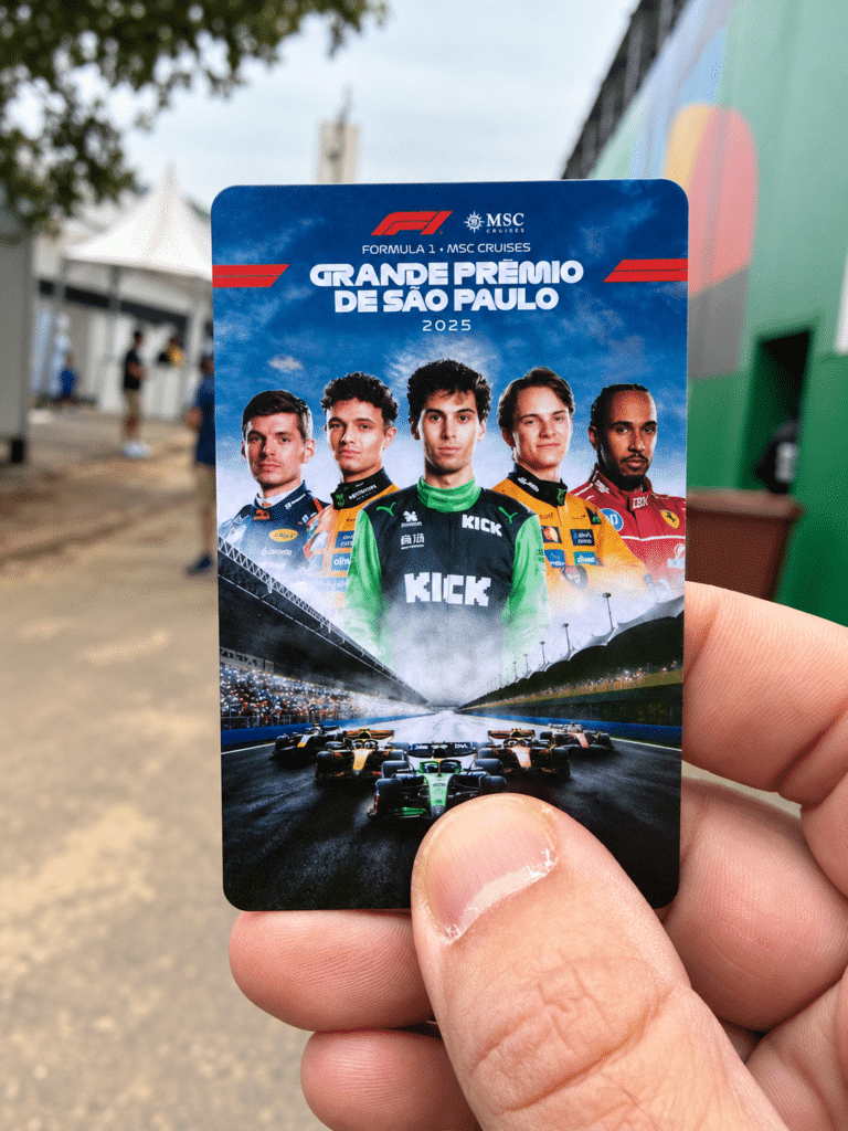 A hand holding a blue 2025 São Paulo Grand Prix cashless payment card featuring Formula 1 drivers and racing artwork.