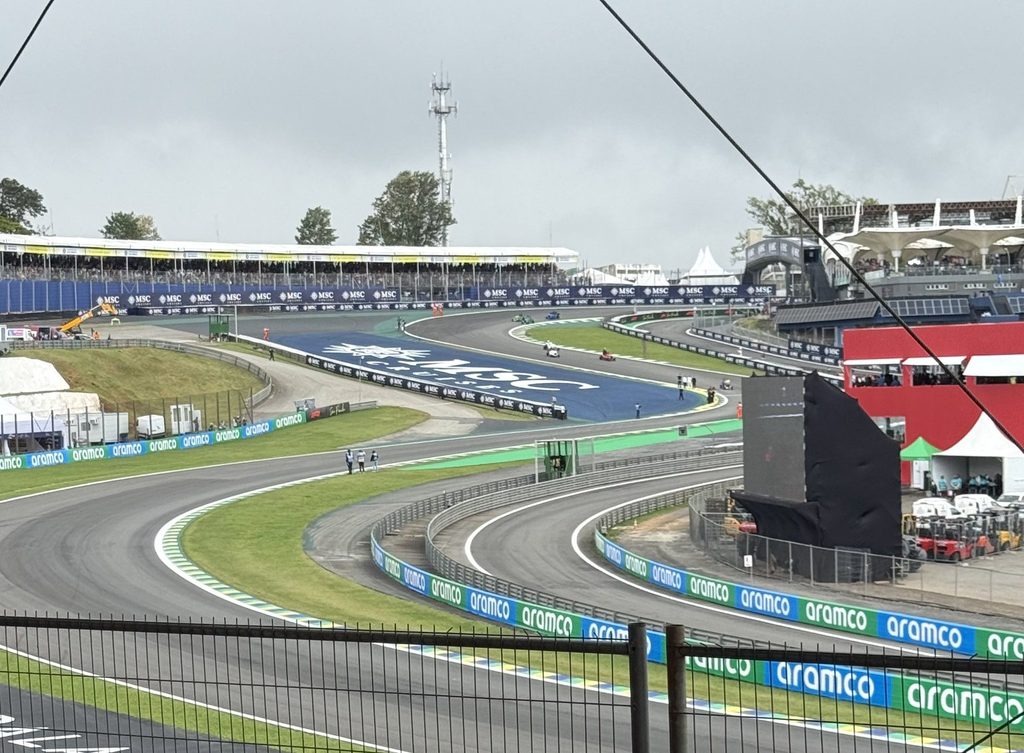 Formula 1 Grandstand The Senna S at Interlagos viewed from the stands, with safety fencing and support cables across the circuit view.